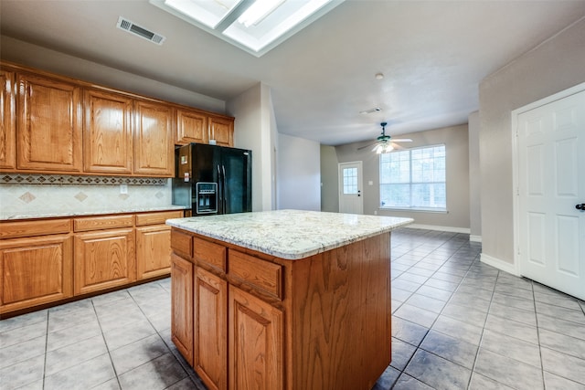 kitchen with ceiling fan, a center island, backsplash, black fridge with ice dispenser, and light tile patterned floors