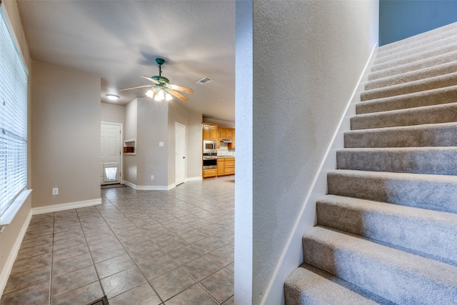 stairway with tile patterned flooring and ceiling fan