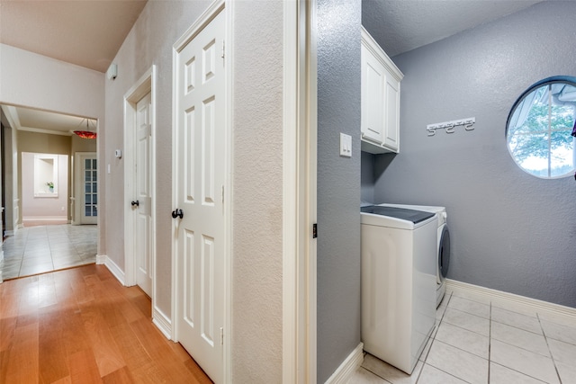 clothes washing area featuring washer and dryer, light tile patterned floors, and cabinets