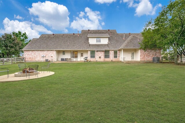 back of property with a fire pit, a patio area, central air condition unit, and a lawn