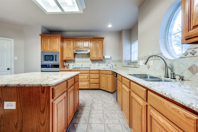 kitchen with light stone countertops, a center island, stainless steel appliances, and sink