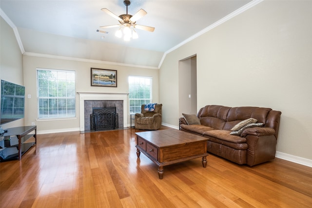 living room featuring hardwood / wood-style floors, crown molding, vaulted ceiling, plenty of natural light, and a tiled fireplace