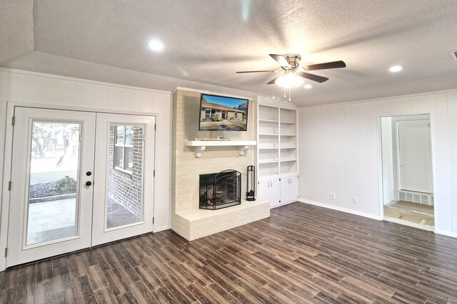 unfurnished living room with ceiling fan, dark hardwood / wood-style floors, lofted ceiling, a fireplace, and french doors