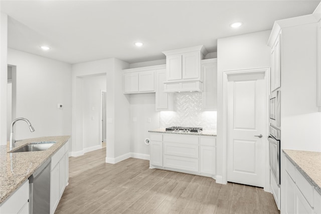 kitchen featuring sink, white cabinets, light stone counters, light hardwood / wood-style floors, and stainless steel appliances