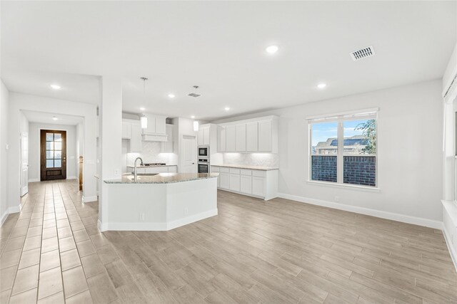 kitchen with sink, white cabinetry, decorative backsplash, decorative light fixtures, and stainless steel oven