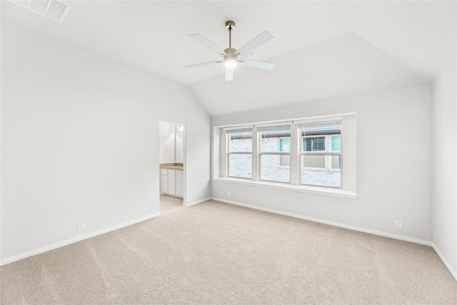 spare room with vaulted ceiling, light colored carpet, and ceiling fan