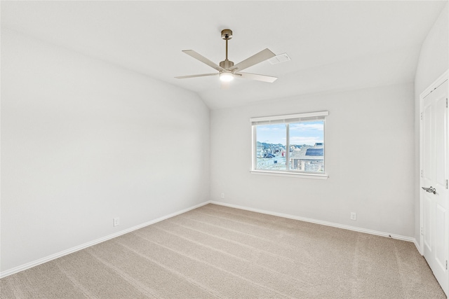 carpeted spare room with ceiling fan and vaulted ceiling