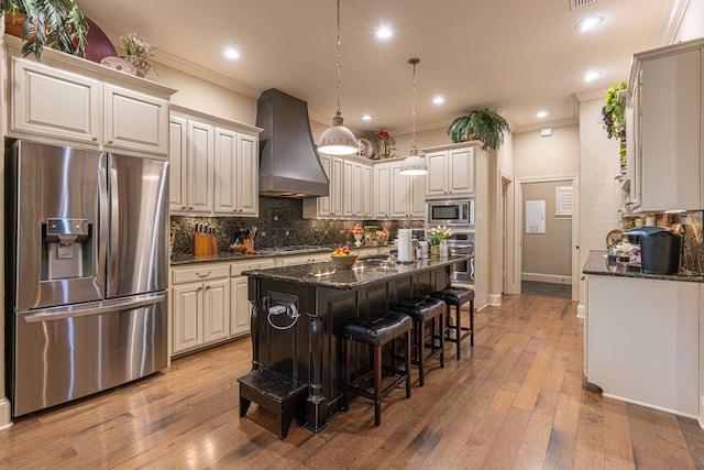 kitchen featuring hardwood / wood-style floors, wall chimney range hood, a center island, and appliances with stainless steel finishes