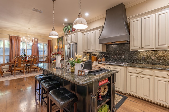 kitchen with ornamental molding, pendant lighting, a breakfast bar, wall chimney exhaust hood, and a center island