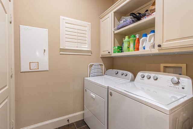 clothes washing area featuring washing machine and dryer, dark tile patterned floors, and cabinets