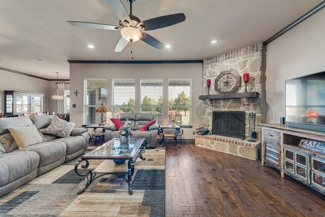 living area featuring a ceiling fan, wood finished floors, a textured ceiling, crown molding, and a fireplace