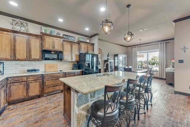 kitchen featuring a sink, decorative backsplash, black appliances, brown cabinetry, and crown molding