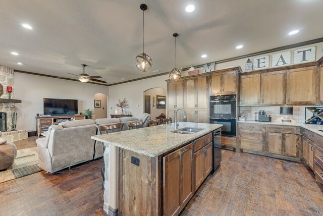 kitchen featuring arched walkways, a sink, open floor plan, ornamental molding, and black appliances