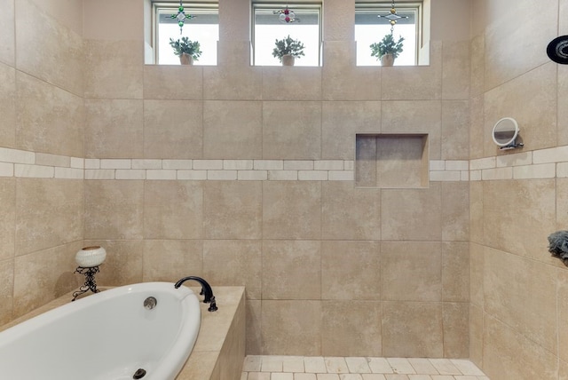 bathroom with a garden tub and tiled shower