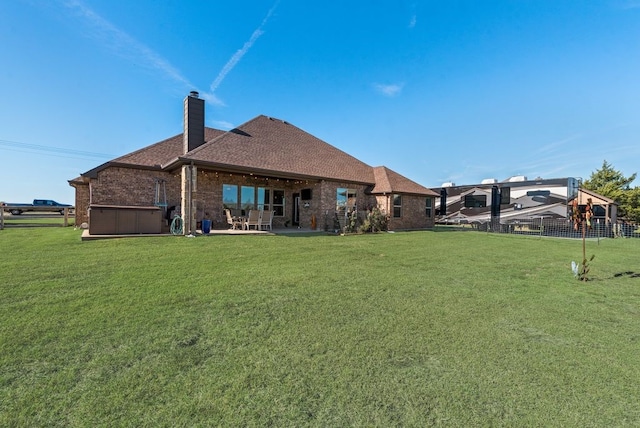 back of property with a patio, brick siding, a chimney, and fence