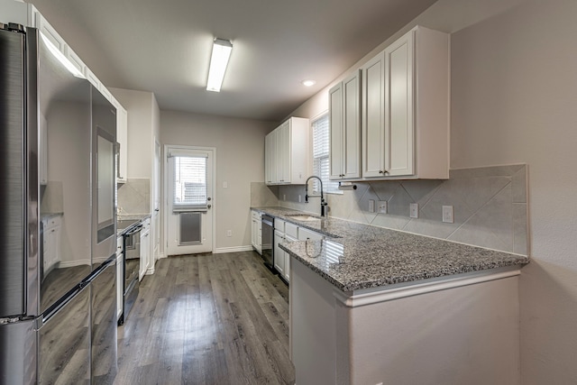 kitchen featuring white cabinetry, sink, light hardwood / wood-style flooring, stone countertops, and appliances with stainless steel finishes