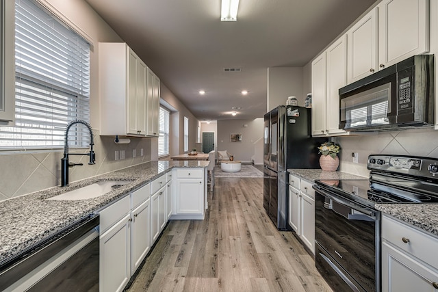 kitchen featuring black appliances, white cabinetry, a wealth of natural light, and light hardwood / wood-style floors