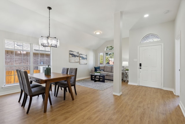 dining area featuring light hardwood / wood-style floors, vaulted ceiling, and a notable chandelier