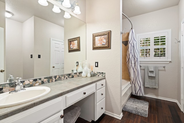 bathroom featuring hardwood / wood-style floors, vanity, shower / bathtub combination with curtain, and a textured ceiling