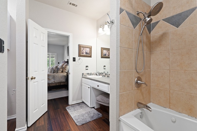 bathroom featuring wood-type flooring, vanity, and tiled shower / bath