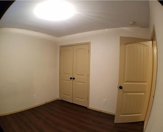 unfurnished bedroom featuring dark hardwood / wood-style floors and a closet