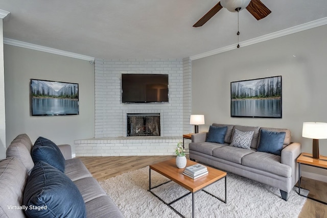 living room with a fireplace, hardwood / wood-style floors, ceiling fan, and ornamental molding