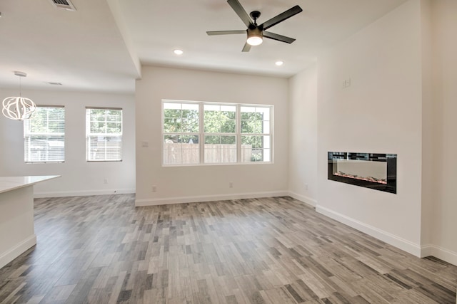 spare room with hardwood / wood-style floors and ceiling fan with notable chandelier