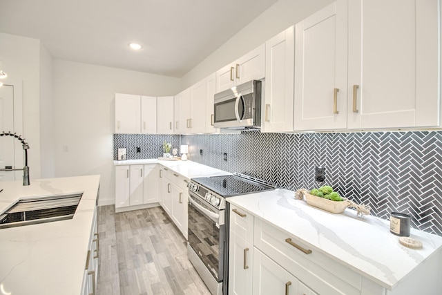 kitchen with stainless steel appliances, white cabinetry, and light stone counters