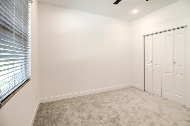 unfurnished bedroom featuring ceiling fan, a closet, and light carpet