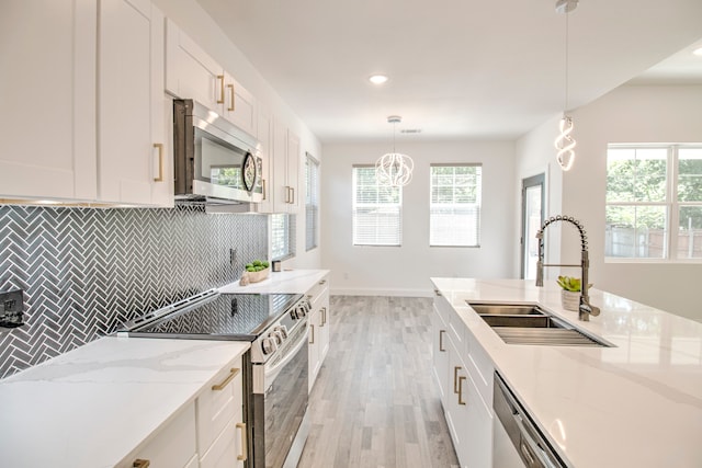 kitchen featuring sink, white cabinets, stainless steel appliances, and decorative light fixtures