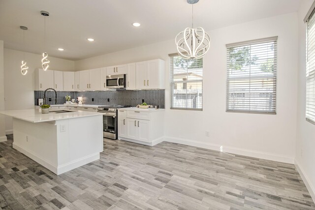 kitchen featuring pendant lighting, sink, appliances with stainless steel finishes, tasteful backsplash, and white cabinetry