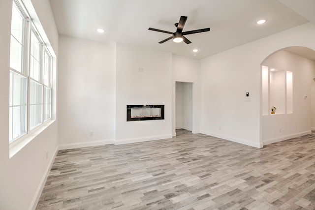 unfurnished living room with ceiling fan, light hardwood / wood-style floors, and heating unit