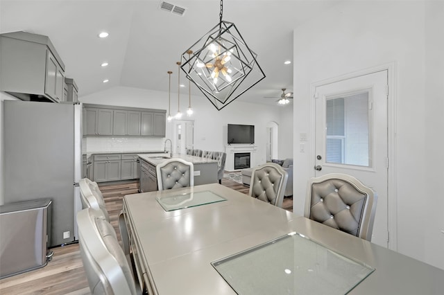 dining area featuring light hardwood / wood-style flooring, ceiling fan, sink, and lofted ceiling