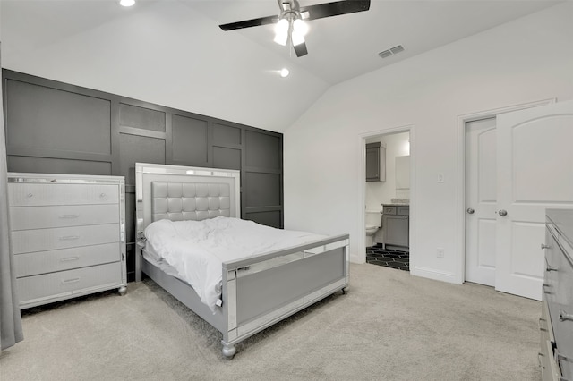 bedroom with vaulted ceiling, ceiling fan, ensuite bathroom, and light carpet