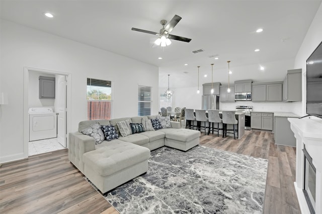 living room featuring washer / clothes dryer, ceiling fan, and wood-type flooring