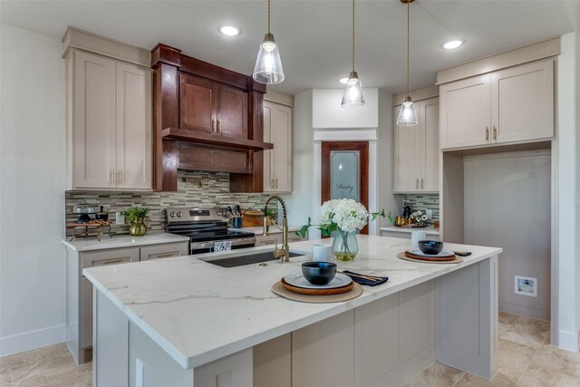 kitchen featuring electric stove, sink, an island with sink, and decorative light fixtures