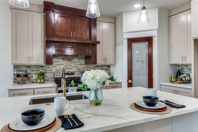 kitchen with decorative light fixtures, tasteful backsplash, light stone counters, and sink