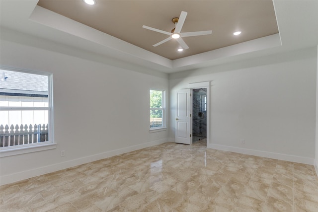 spare room with a tray ceiling and ceiling fan