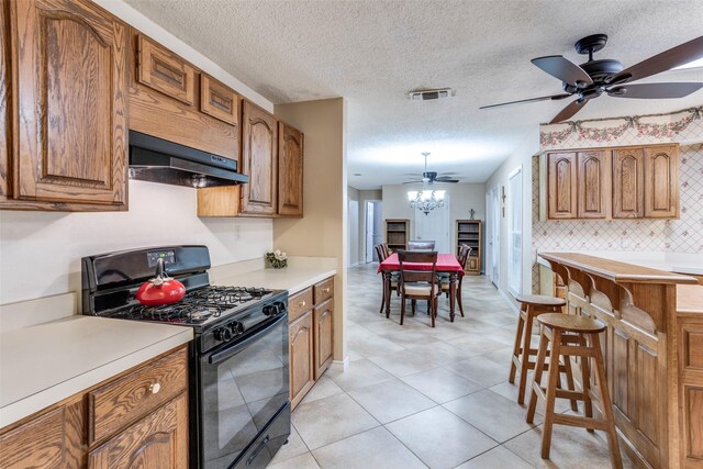 kitchen featuring ceiling fan, black gas range oven, tasteful backsplash, range hood, and light tile patterned flooring