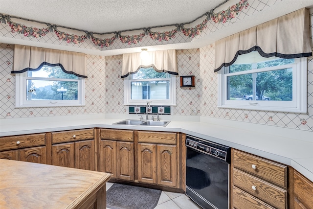 kitchen with sink, black dishwasher, a healthy amount of sunlight, and a textured ceiling