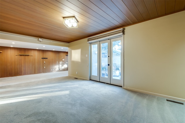 unfurnished room with wood walls, french doors, light colored carpet, and wood ceiling