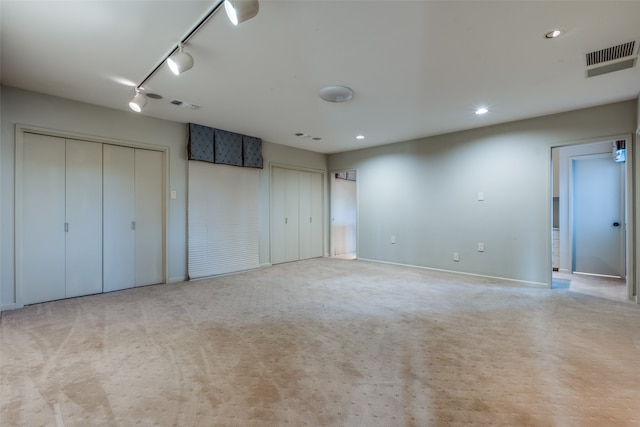 unfurnished bedroom featuring light carpet and two closets