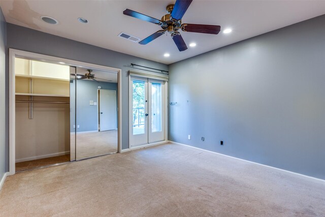 unfurnished bedroom featuring ceiling fan, a closet, light colored carpet, and french doors