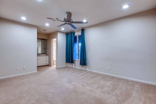 unfurnished bedroom featuring connected bathroom, ceiling fan, and light colored carpet