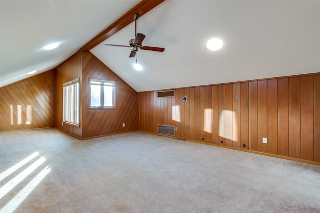 additional living space with vaulted ceiling with beams, light colored carpet, ceiling fan, and wood walls