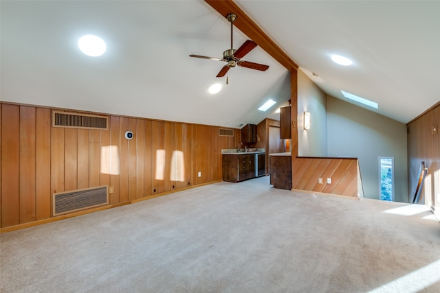 additional living space with wood walls, light carpet, and lofted ceiling with skylight