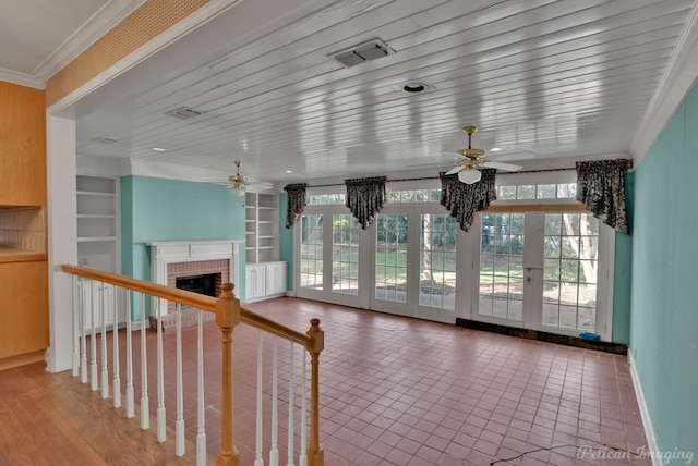 unfurnished living room featuring ornamental molding, a fireplace, built in shelves, tile patterned flooring, and french doors