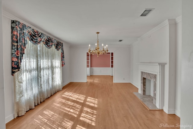 unfurnished living room with ornamental molding, hardwood / wood-style floors, a chandelier, and a premium fireplace