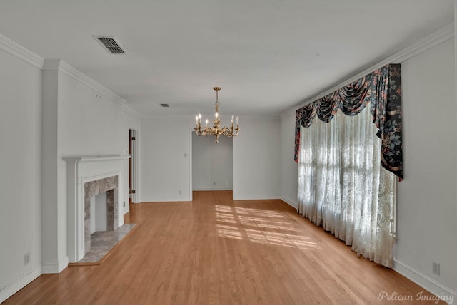 unfurnished living room featuring a fireplace, crown molding, light hardwood / wood-style flooring, and a chandelier