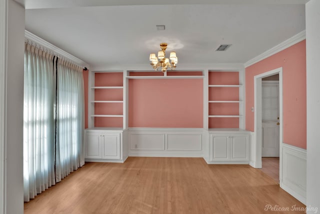 empty room featuring light hardwood / wood-style flooring, crown molding, built in features, and an inviting chandelier